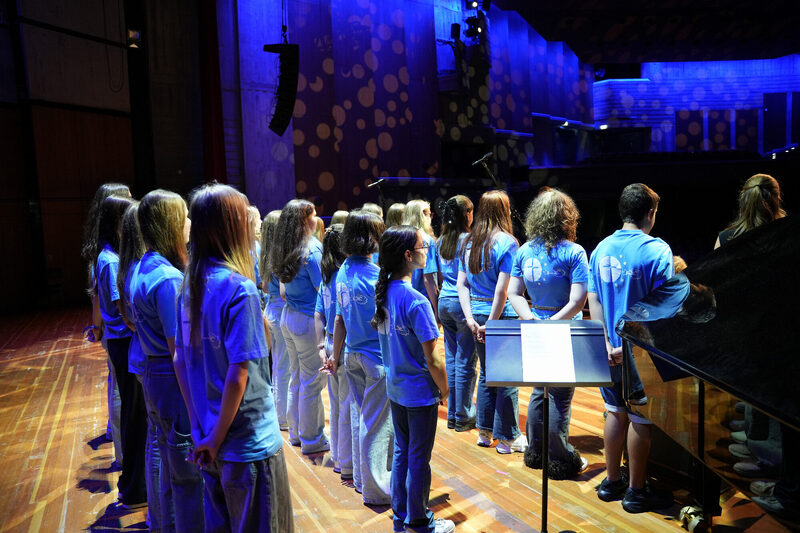 Schülerchor in hellblauen T-Shirts auf der Konzertbühne, Best of Schulwerk 2026